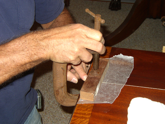 A large C-clamp and wooden blocks surfaced with wax paper made sure the joint was level before applying pressure on the long clamps.