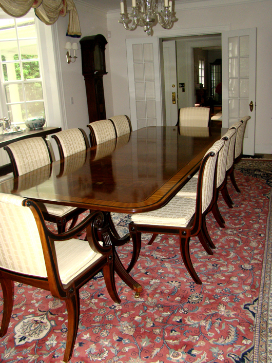 Baker custom-crafted dining suite with banded-inlay table, four leaves, two captain’s chairs and 12 side chairs with original ivory silk-blend upholstery. TAC Auctions image.