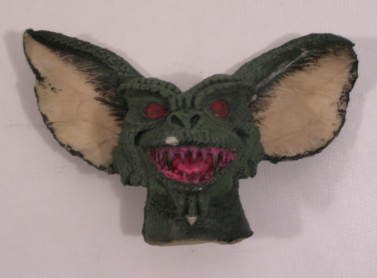 From the 1984 Joe Dante film 'Gremlins' comes an unfinished rubber Gremlin head. The head is made from soft foam rubber and painted green. Premiere Props image.