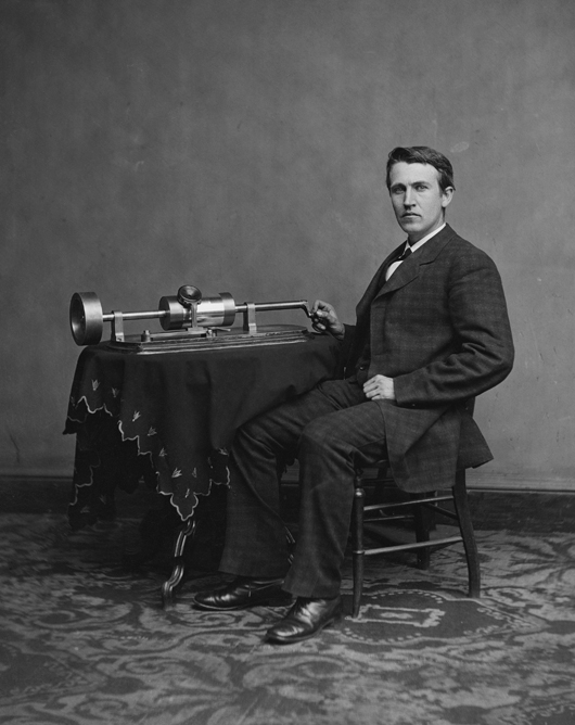 Thomas Edison and his early phonograph, circa 1877. Cropped from US Library of Congress copy.