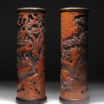 Pair of Chinese carved bamboo incense cylinder, carved with continuous landscape of figures conversing and playing games beneath a large openwork pine tree. 25 centimeters high by 8.2 centimeters diameter. Joyce Gallery Auction image.