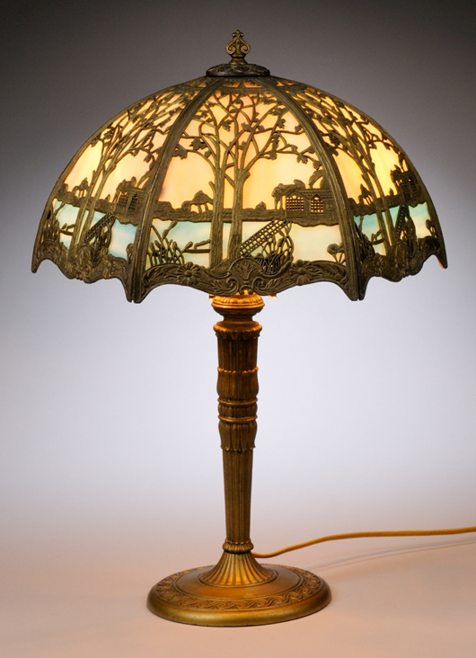 Hexagonal gilt-metal overlay slag glass panel table lamp with cast metal base, approximately 23 inches high by 16 1/2 inches wide. Estimate: $500-$700. Skinner Inc. images.