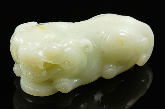  White jade foo lion, China, carved in the form of a mythical lion in a crouching pose holding a coin, 4 inches long. Kaminski Auctions image.