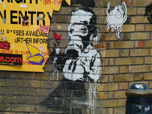Photo of a Banky work in Brick Lane, East End, in 2004. Image by Matt Whitby, courtesy of Wikimedia Commons. 