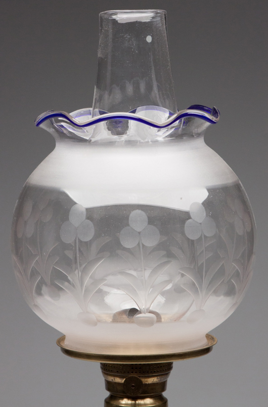 A cut and frosted ball-form shade with rare applied blue rim, a lip burner by E.F. Jones with a Merrill’s air director, a shade ring with edge coining, and a lip chimney, sold for $1092.50. Jeffrey S. Evans & Associates image.