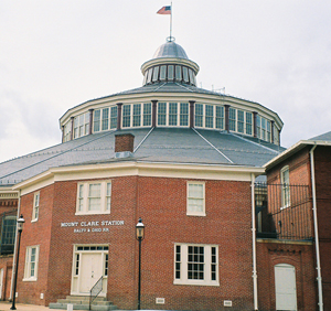 The Baltimore & Ohio Railroad's passenger station, built in 1851, and roundhouse in the background and now part of the B&O Railroad Museum. Image by James G. Howes, courtesy of Wikimedia Commons.