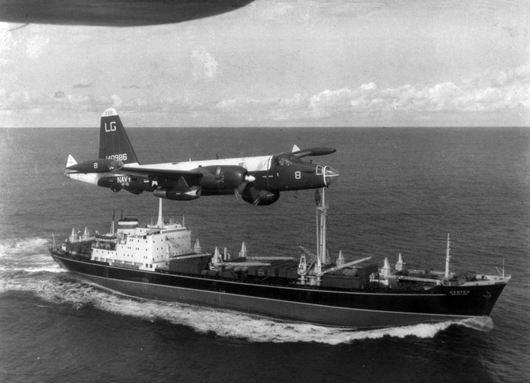 A U.S. Navy P-2H Neptune of VP-18 flying over a Soviet cargo ship with crated II-28s on deck during the Cuban Crisis. Image courtesy of Wikimedia Commons. 
