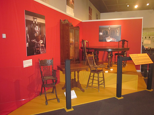 The exhibit area is divided into five room settings in a house. This space, the dining room, features a variety of high chairs, dining table with chairs, and a china cabinet. Courtesy of the Museum of the South Dakota State Historical Society.