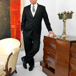 Palm Beach Modern’s auctioneer, Rico Baca, gets into the Gatsby mood as he inspects premier items in the company’s May 25 auction, including (clockwise from left) one of a pair of Jules Leleu French Art Deco period chairs with ottomans, a large Jeff Compertz abstract painting, one of a pair of circa-1930 French Art Deco Egyptian Revival candelabra, and an Alfred Porteneuve French Art Deco rosewood with silver-plated bronze sideboard/dresser made in 1939 for the SS Pasteur ocean liner. Palm Beach Modern Auctions image.