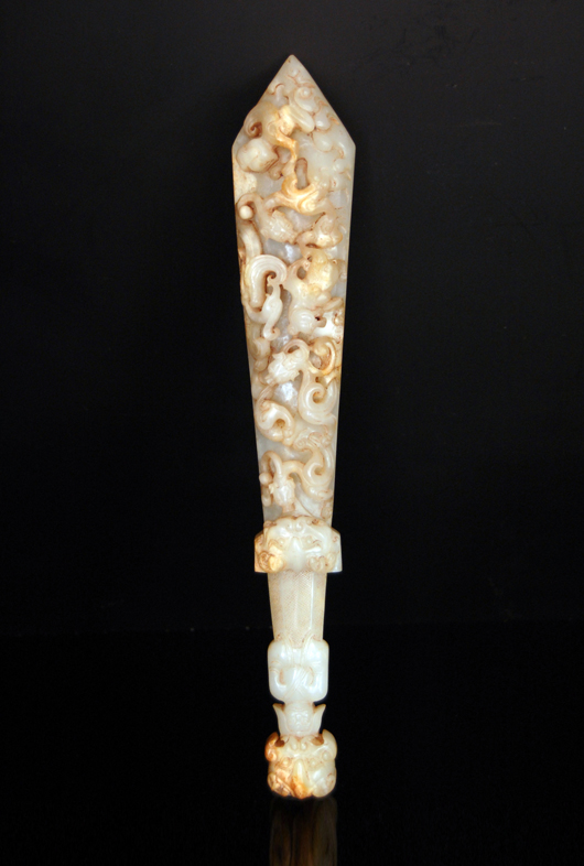Han Dynasty white jade ritual dagger with high-relief carvings of entwined Qilins on one side and archaistic motifs on the back. The long handle bears the carving of a figure. Gianguan Auctions image.
