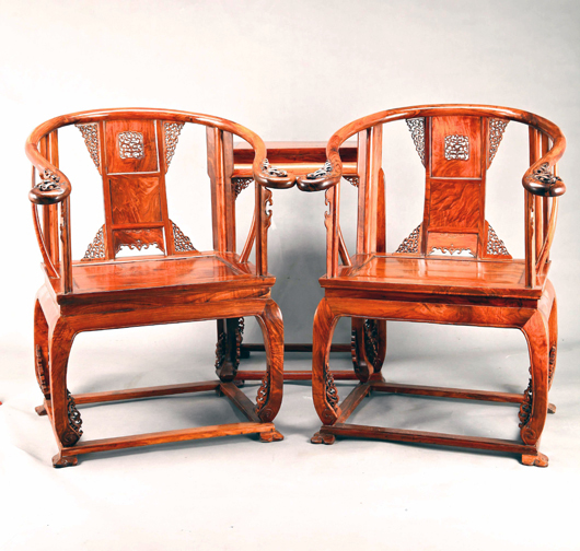 Pair of ornately carved huanghuali wood armchairs with horseshoe-shape backs, pierced conforming splats, box stretchers and satin cushions. Estimate $16,000-$24,000. Linwoods image.