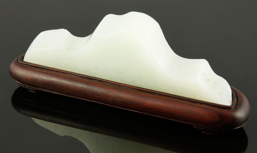 White jade brush holder, China, with carved Shiru mark, carved in the form of a mountain range, on a zitan wood stand, 1 5/8 inches x 4 3/4 inches. Price realized: $5,000. Kaminski image.