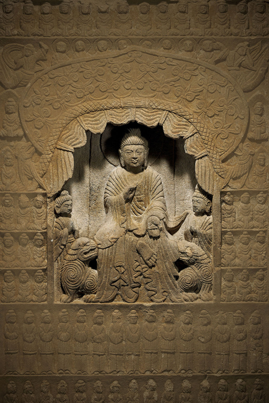 Massive antique Chinese carved stone stele featuring a seated Buddha in a grotto niche and flanked by attendants, and surrounded by numerous deities and attendants. The slab is 33 inches high. I.M. Chait image.