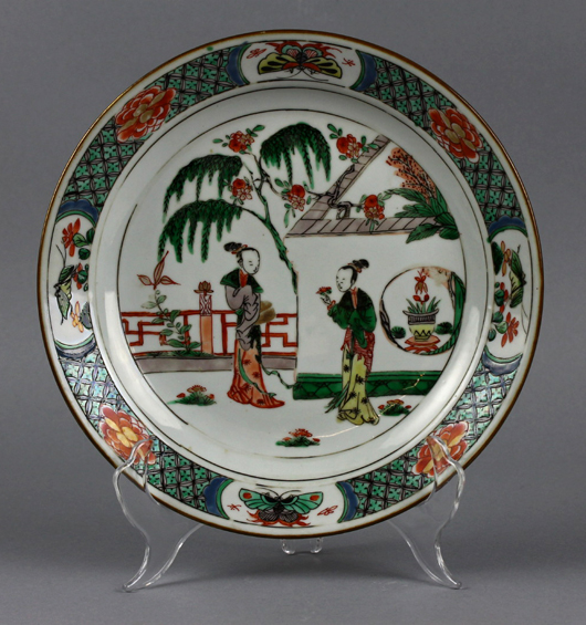 Brightly enameled 17th-century Kangxi Period Chinese famille verte plate with image of elegant ladies in garden, decorative border with winged insects in cartouches, 9¼in diameter. Est. $2,000-$5,000. Manatee Galleries image.