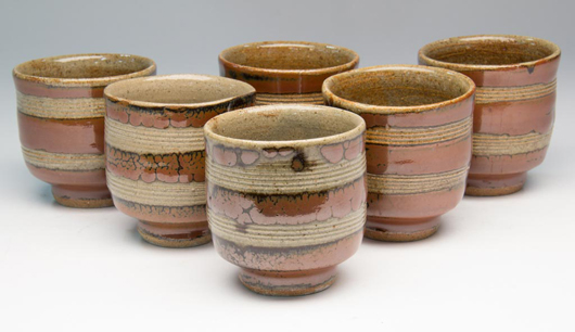 Japanese studio pottery group of six stoneware tenmoku-glazed footed tea bowls, Mashiko-area, attributed to Shoji Hamada, 3 3/16 inches high, sold for $4,313. 