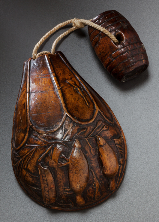 Eastern woodlands carved wood belt cup, circa 1760, carved of maple burl, depicting two beavers, a sailing ship, two flintlock guns and a broom-like object, the barrel-shape toggle attached with string, 4 3/4 inches. Estimate: $10,000-$20,000. Heritage Auctions image.