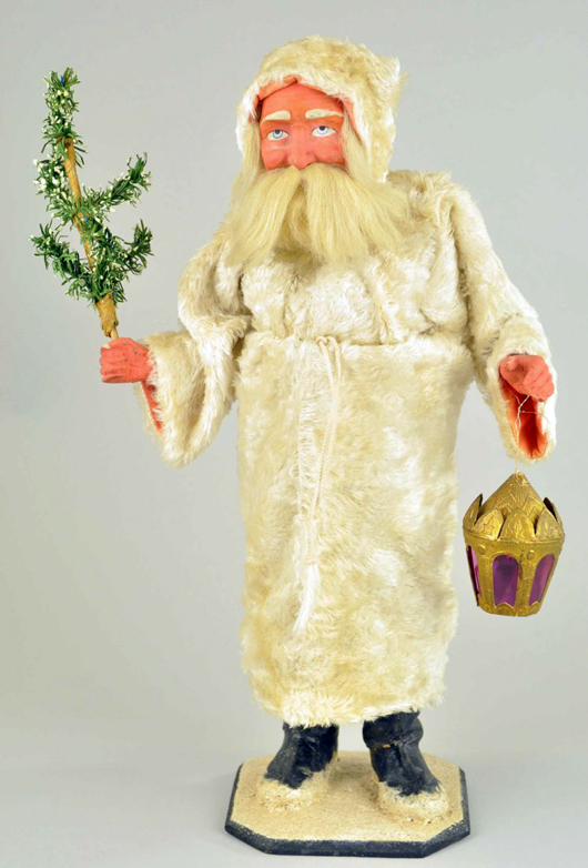Large candy container depicting Father Christmas, Germany, composition feet, hands and face, carrying a Dresden lantern and a paper tree, 18 1/2 inches. Image courtesy of LiveAuctioneers.com Archive and Bertoia Auctions.
