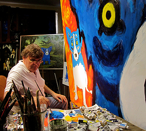 George Rodrigue at work on a large canvas featuring his signature 'Blue Dog.' Image courtesy of The George Rodrigue Foundation Inc.
