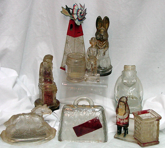 Examples from a collection of 60+ early glass candy containers, some with paint or original metal accessories. John W. Coker Auctions image.