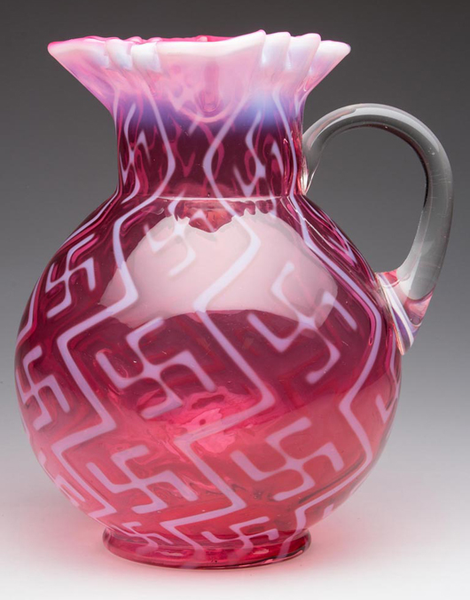 Lot 453: Swastika pattern water pitcher of cranberry opalescent glass, Dugan Glass Co., circa 1904, 9 inches high. Price realized: $6,900. Jeffrey S. Evans & Associates image.
