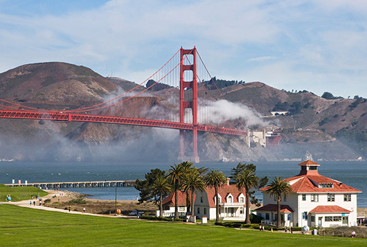 The former Coast Guard Station at the Presidio, with the Golden Gate Bridge in the background. Image by Will Elder, courtesy of Wikimedia Commons.
