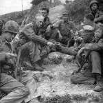 Ernie Pyle (second from left) shares a cigarette with U.S. Marines on Okinawa in 1945. Image courtesy of Wikimedia Commons.