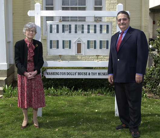 2004 photograph of Flora Gill Jacobs and Noel Barrett in front of the Washington Dolls’ House & Toy Museum. Photo was taken shortly before Barrett’s auction of the museum’s contents. Noel Barrett Auctions image.
