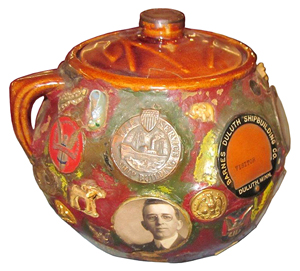A tobacco jar was used to make this memory jar. Decorating it are campaign buttons and badges, a war service shipbuilding medal, a Duluth, Minn., shipbuilding visitor's badge, a china shoe, small anchor and other items from the 1930s. It sold at Old Barn Auction in Findlay, Ohio, for just $72, probably because it had a chip on the lid.