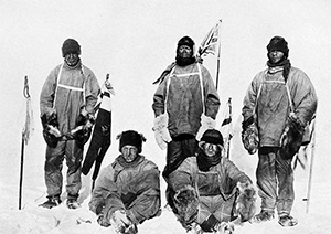 Robert Falcon Scott's Pole party of his ill-fated expedition, from the left: Oates (standing), Bowers (sitting), Scott (standing in front of Union Jack flag on pole), Wilson (sitting), Evans (standing). Image courtesy of Wikimedia Commons.
