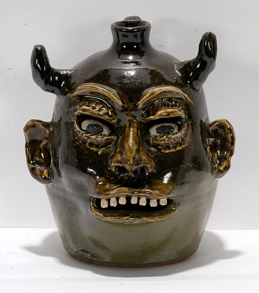 Lot 75 – Lanier Meaders, devil jack-o’-lantern face jug. c. 1970s, signed, opening in back for candle, 10in high. Est. $3,000-$5,000. Slotin Folk Art image.