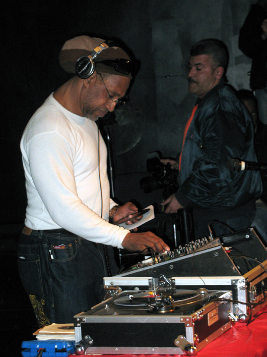 Jamaican-born DJ Kool Herc, who originated hip hop music in the early 1970s in the Bronx, New York City, promoted hard funk music as an alternative to the violent gang culture of his neighborhood. In this February 28, 2009 photo taken by Bigtimepeace, Kool Herc spins records in the Hunts Point section of the Bronx at an event addressing 'The West Indian Roots of Hip Hop.'