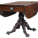 This Empire drop-leaf table, circa 8130, has as solid mahogany top and base with crotch cut mahogany veneer on the drawer front and skirt.