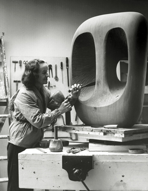 Barbara Hepworth in the Palais studio in 1963 with unfinished wood carving 'Hollow Form with White Interior.' Photograph by Val Wilmer, courtesy Bowness, Hepworth Estate.