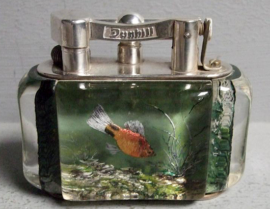 A Dunhill 'Aquarium' table petrol lighter, circa 1950, the clear body decorated in reverse with fish among aquatic foliage. It sold for £1,500. Photo: Ewbank’s Auctions