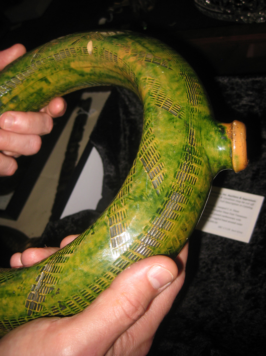John Case shows off the perfect condition and circular form of the Haun ring bottle. An elaborate impressed pattern enlivens the vessel’s green-glazed surface. Image courtesy Case Antiques.