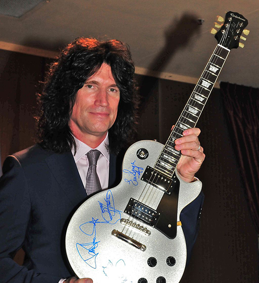 Kiss guitarist Tommy Thayer holding an autographed guitar at the 2013 benefit event for the Oregon Military Museum. Image by oregonmildep. This file is licensed under the Creative Commons Attribution 2.0 Generic license.