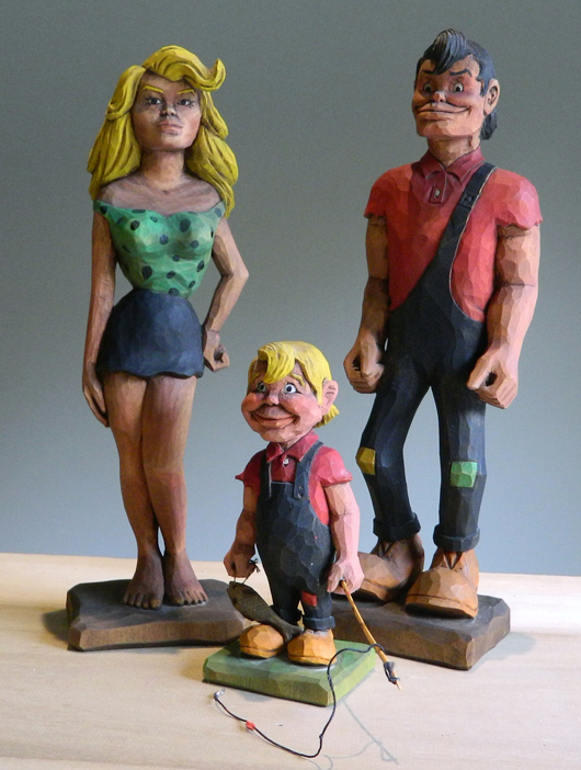 Wood-carver Harold Enlow's depiction of Dogpatch characters Daisy Mae Yokum, Li’l Abner Yokum and their son Honest Abe Yokum. Image courtesy of Don Arnett and the Boone County (Ark.) Heritage Museum.