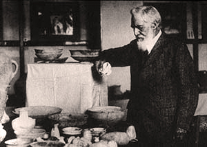 British archaeologist Sir William Matthew Flinders Petrie  exhibiting material from a site in Iraq, circa 1922. Image courtesy of Wikimedia Commons.