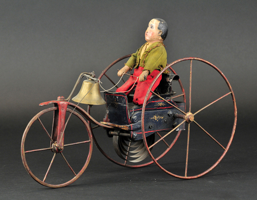 Boy on clockwork tricycle, cast-iron frame with tin open card, hand-painted all-wood figure, 16in long, est. $6,000-$7,500. Bertoia Auctions image