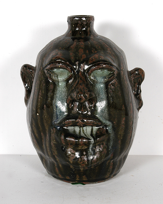 Lanier Meaders, ‘Runny Eyes and Teeth Face Jug,’ c. early 1980s. One of approximately 80 from a kiln of mistakes. This group is famous for the melted effect and beautiful deep rich dark tobacco-spit glaze, 10 1/2 in. high. Est. $1,500-2,500. Slotin Auction image.