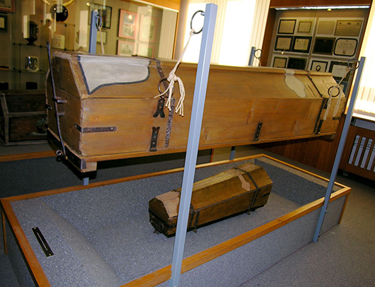 An infamous reusable coffin instigated in 1784 by Emperor Josef II in an effort to conserve wood. The coffins were equipped with a trap door underneath to drop the bodies in the graves. Image by Ekehnel. This file is licensed under the Creative Commons Attribution-ShareAlike 2.5 Generic license.