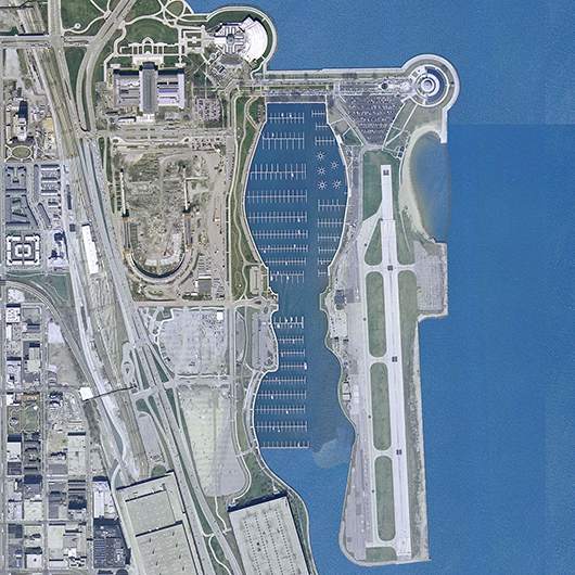 Aerial view from 2002, showing the Chicago lakefront, Soldier Field under renovation, and the parking lot where the Lucas  Museum of Narrative Art is to be built. Meigs Field, a single-strip airport that closed in 2003, is on the right. Image courtesy of Wikimedia Commons.