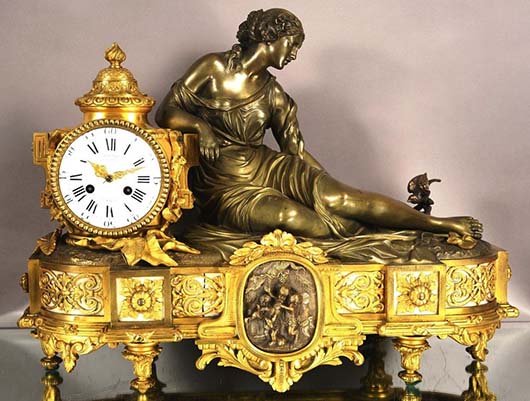 French dore gilt bronze mantel clock with ormolu, depicts lady feeding nest of birds in a pond to her left, solid bronze case with marble inserts and foliage, signed, est. $1,600-$2,400. Bruhns image