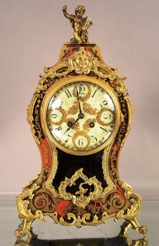 French Louis XIV-style boulle mantel clock, bronze finial with cherub sitting on top, decorated porcelain dial with bronze overly, time and strike, signed, Japy Freres movement, est. $1,300-$1,800. Bruhns image