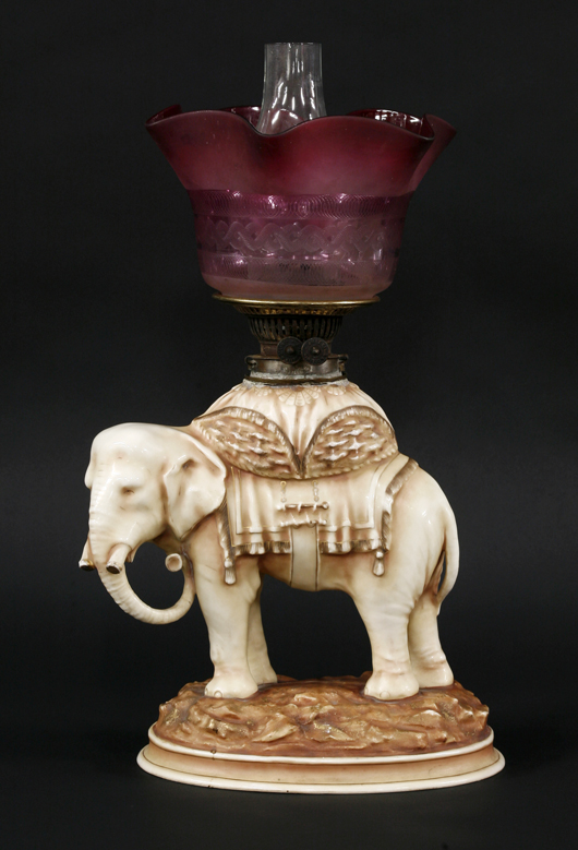 Victorian elephant oil lamp with a cranberry and etched glass shade, 49cm high. Estimate: £400-£500. Sworders image