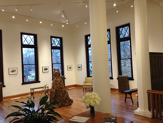 The hardwood floor of the former library supports a dress made of 1,000 pinecones. Image courtesy of Clarinda Carnegie Art Museum