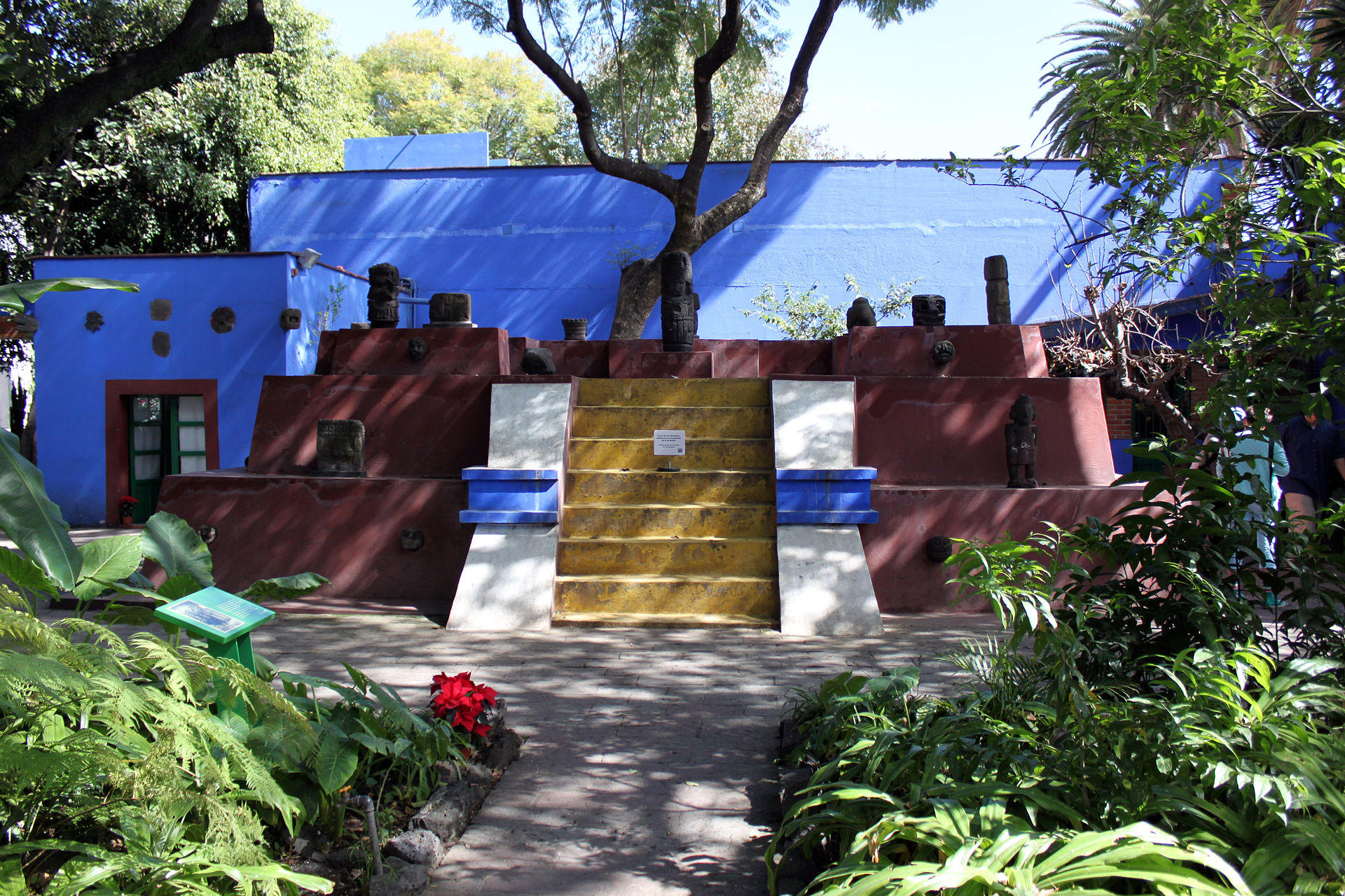 A tomb in the form of a pyramid is the focal point of the garden at Frida Kahlo Museum in the Coyoacan suburb of Mexico City. The museum was Frida Kahlo's residence and studio, and is known as Casa Azul, or Blue House. December 22, 2013 photo by Anagoria, licensed under the Creative Commons Attribution 3.0 Unported license.