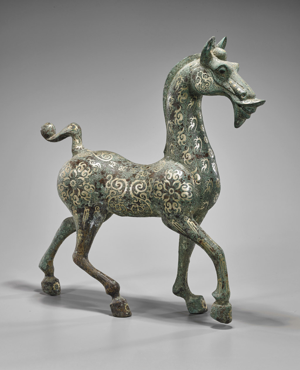 Chinese Han-style inlaid bronze prancing horse, inlaid archaistic flowers and designs to body, 17 1/2in high. Estimate $300-$500. I.M. Chait image.