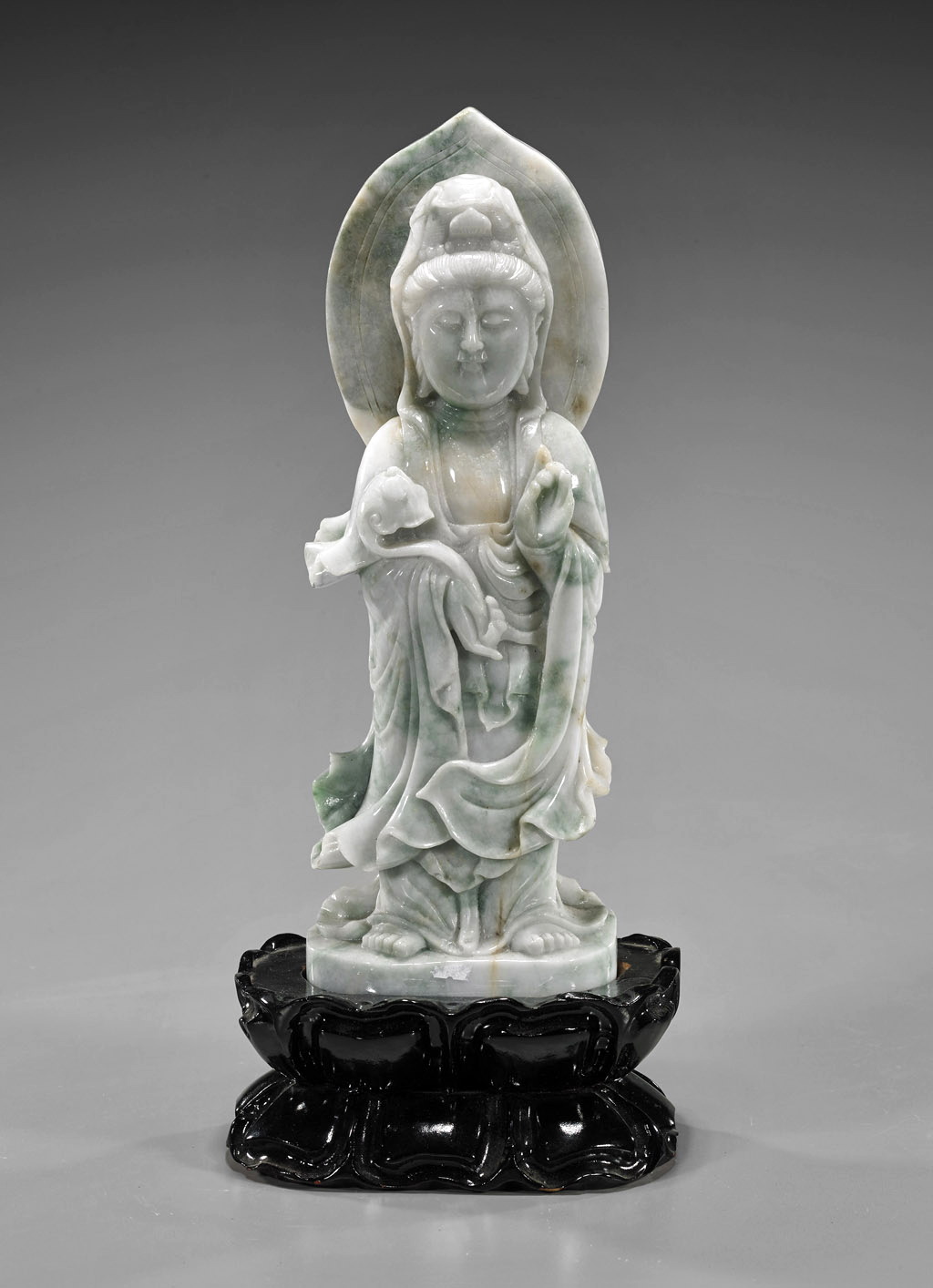 Chinese carved jade Guanyin of celadon color with hints of spinach green and russet suffusions, 12in, with double lotus wood stand. Estimate $1,000-$1,500. I.M. Chait image