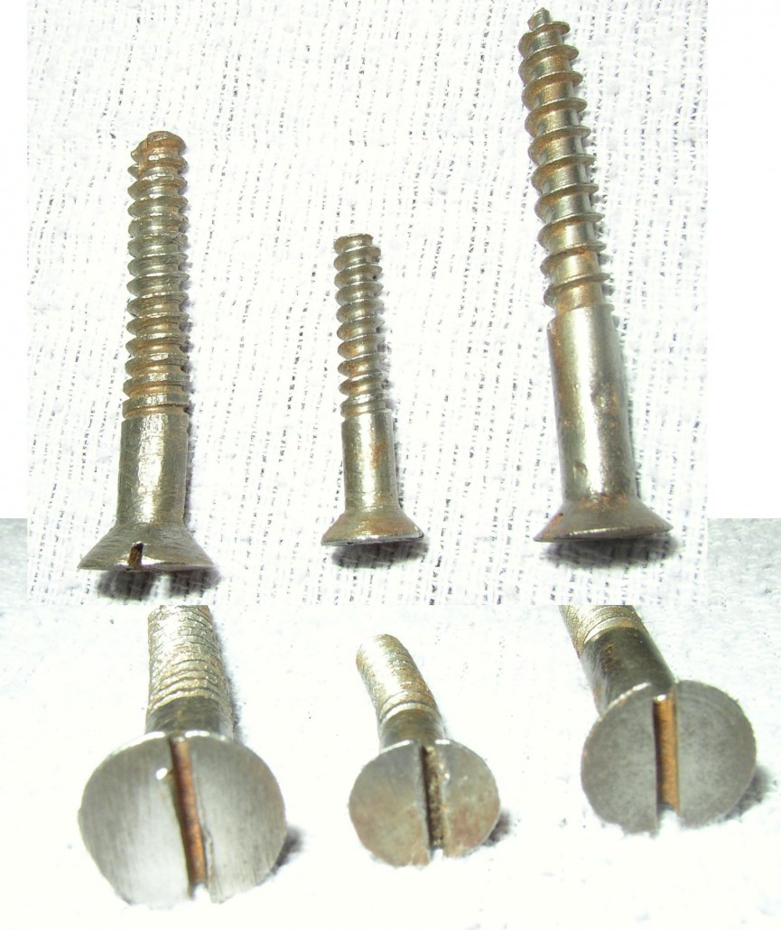 Two views of three screws: The one on the left was handmade in the late 18th century. Note the flat spot on the shaft, the irregular threads, blunt tip and the off-center slot. The screw in the center is machine-made around 1830. It has sharp, even threads, a cylindrical shape, blunt end and the slot is again off-center. The screw on the right is a modern gimlet screw, post 1848, with tapered shaft, even threads, pointed tip and centered slot.